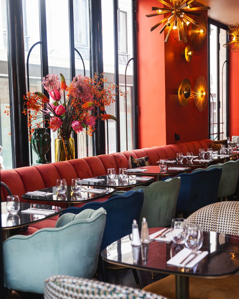 Banquette corail et bouquet de saison devant les fenêtres des Pipelettes du Boulevard